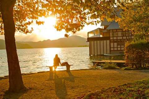 Mann sitzt bei Sonnenuntergang am See