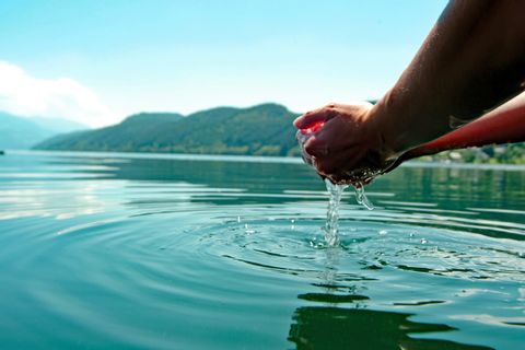 Hände schöpfen Wasser aus einem See